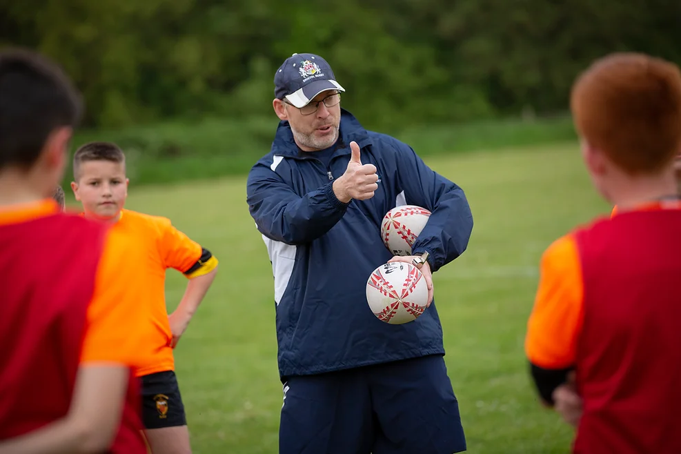 A rugby coach giving positive reinforcement to some young players