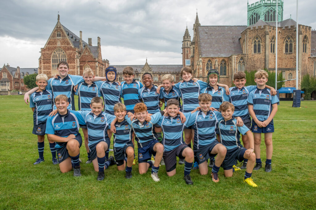 Young rugby players in a team photo outside a school