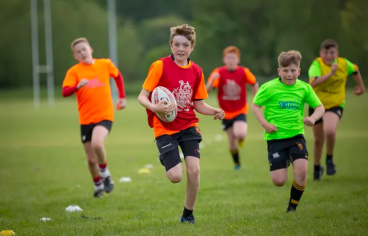 young switch rugby academy players training on the field and running with the ball