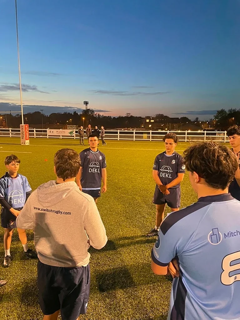 Experienced coach instructing City of Bristol Rugby U16s players during an evening training session – expert guidance to develop rugby skills