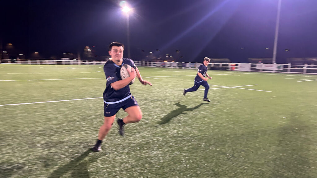 Switch Rugby's City of Bristol youth rugby training session with players running drills on floodlit rugby pitch at night